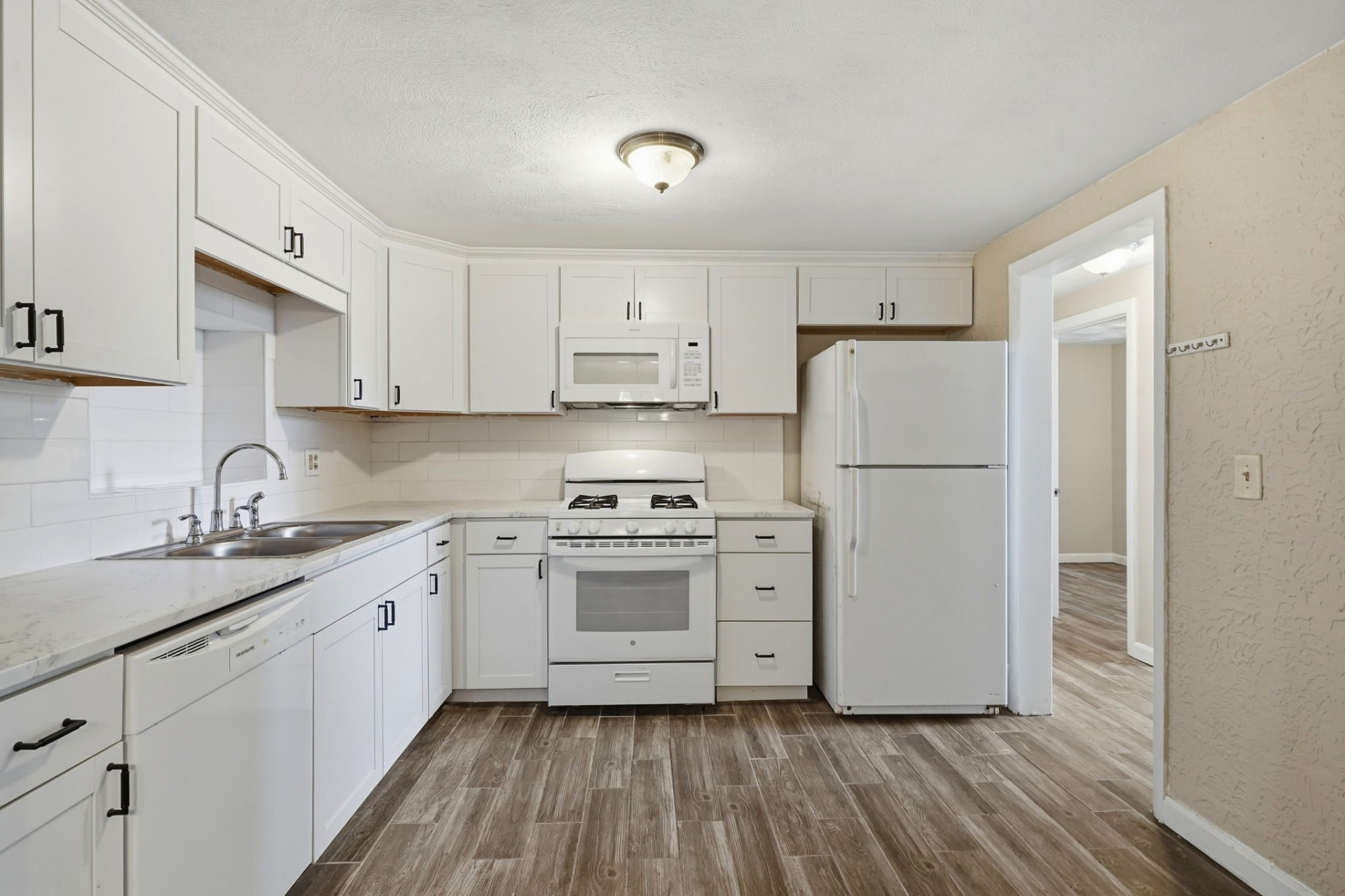 White kitchen with shaker cabinets and wood-look floors